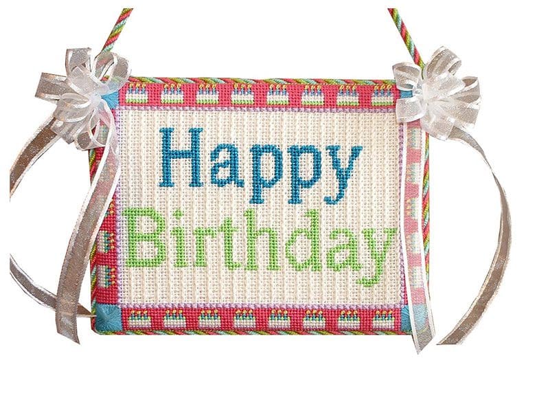 A CBK Needlepoint happy birthday sign hanging on a string at the Finishing Gallery.