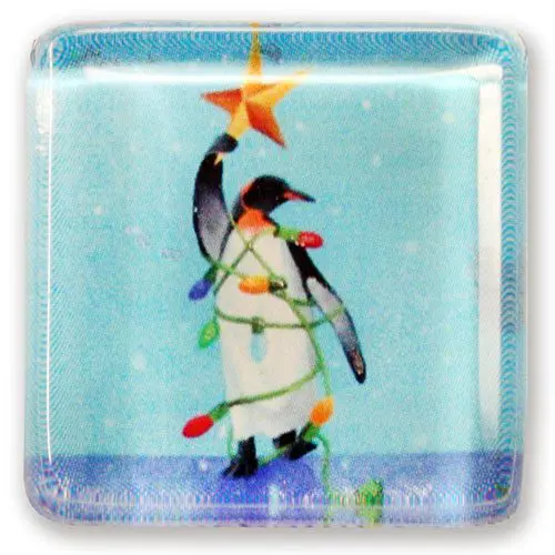 A penguin holding a Needlepoint christmas star on a square glass plate.