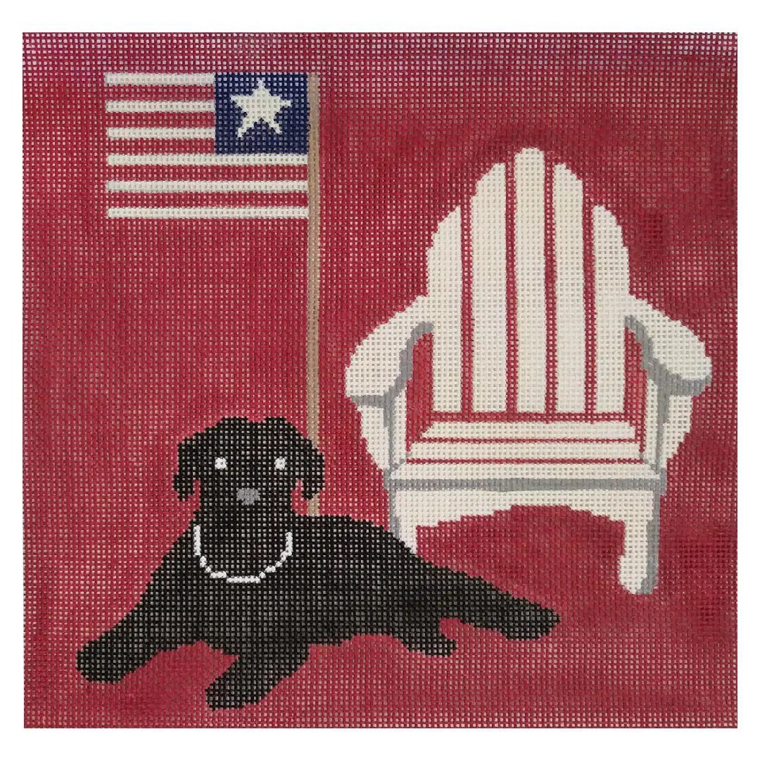 A black lab with an American flag lounging on a red Adirondack chair.