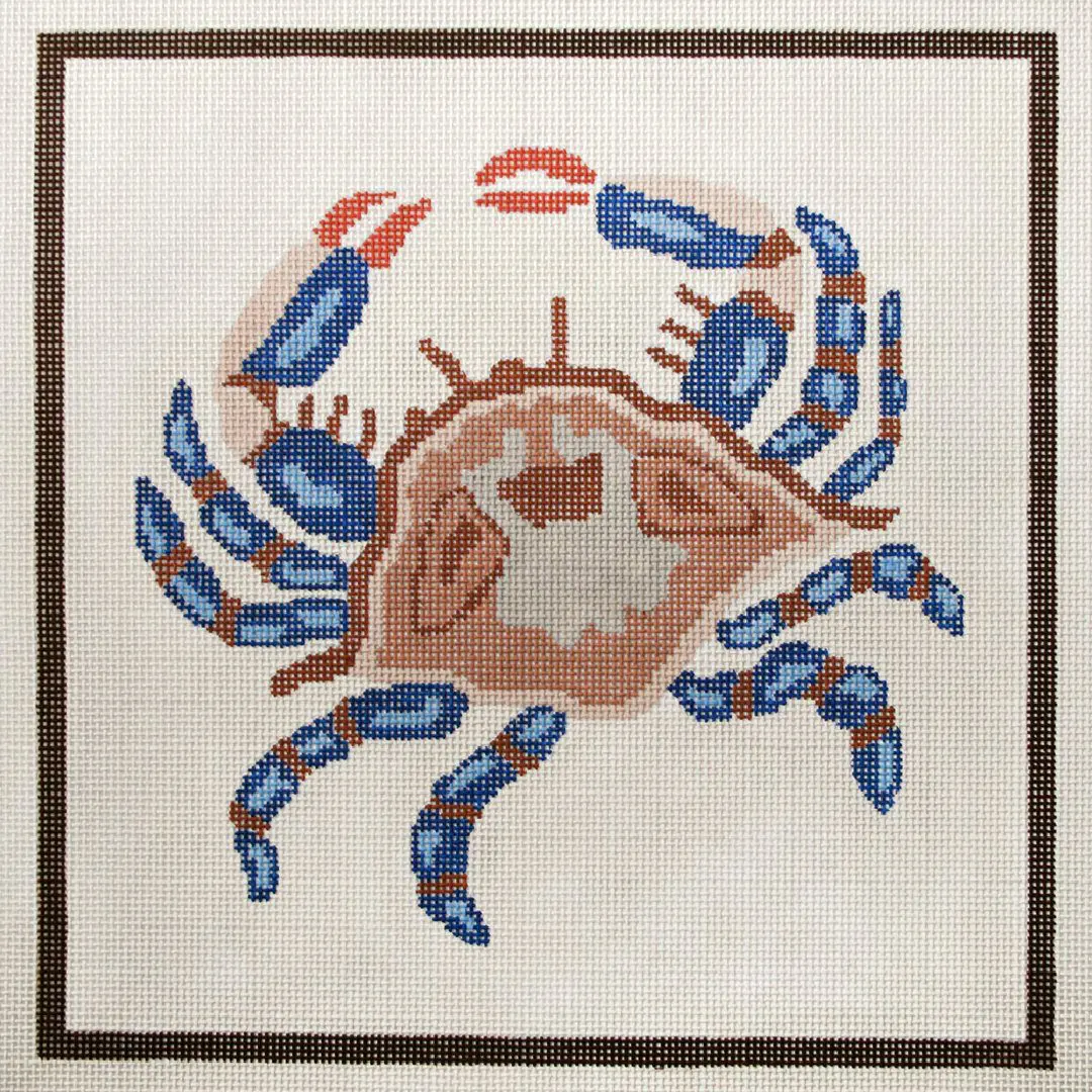 A cross stitch pattern of a crab in blue and brown, designed by Cecilia Ohm Eriksen.