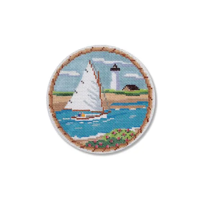 A cross stitched image of a sailboat with a lighthouse in the background.