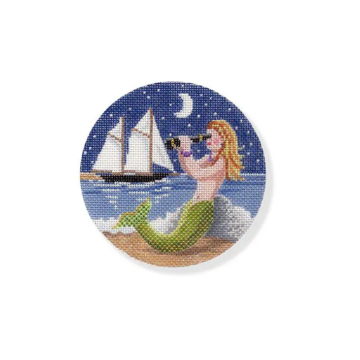 A mermaid sitting on the beach with a sailboat in the background.