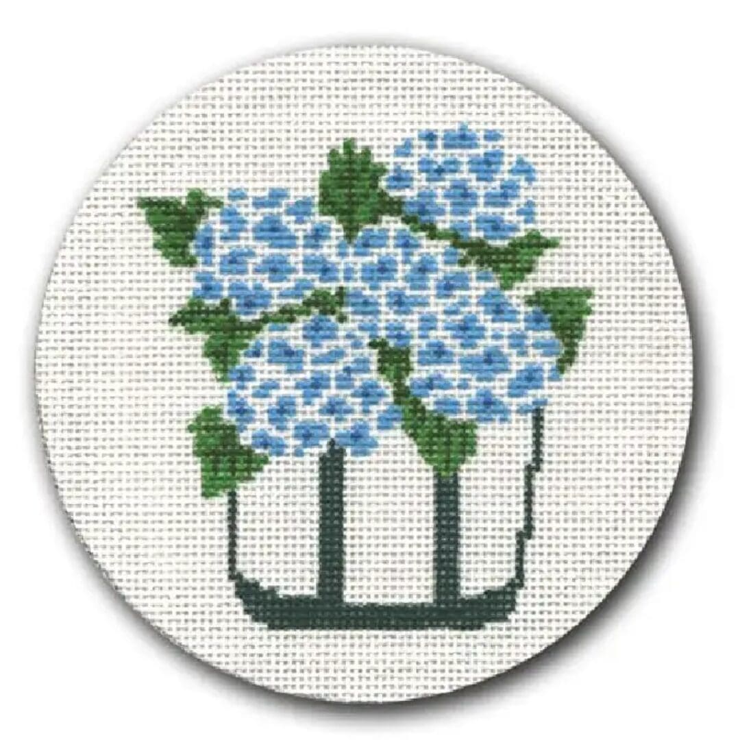 A cross stitch picture of blue flowers in a vase by Cecilia Ohm Eriksen.
