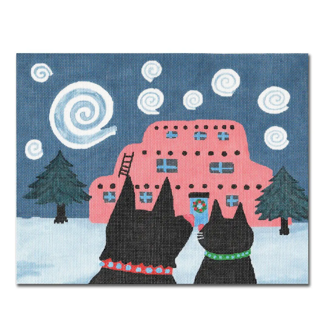 Two black dogs standing in front of a house in the snow.