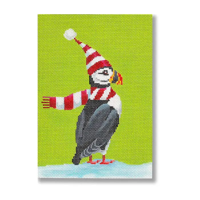 A cross stitch picture of a puffin wearing a hat and scarf.