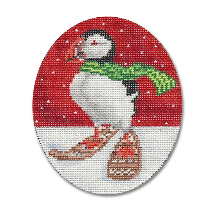 A cross stitch picture of a puffin wearing a scarf and mittens.