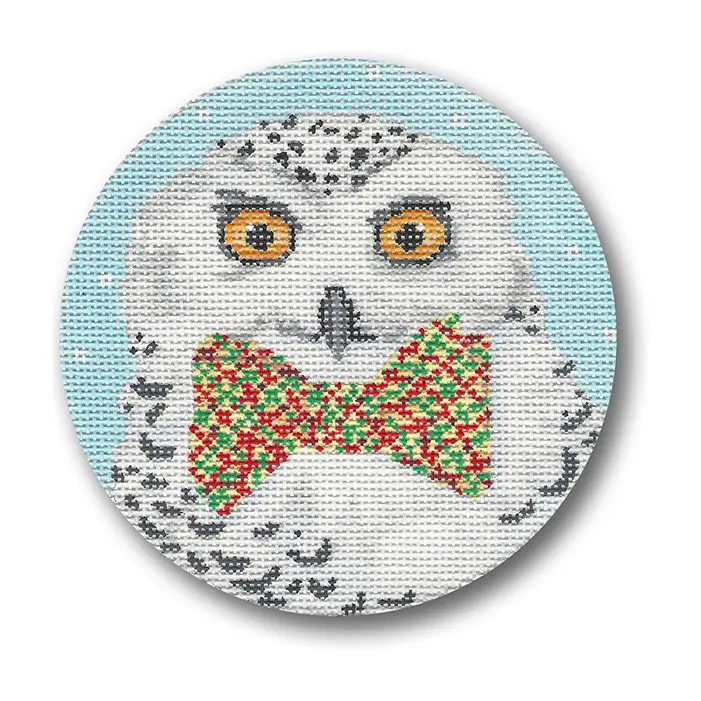 A snowy owl with a bow tie on a round canvas.