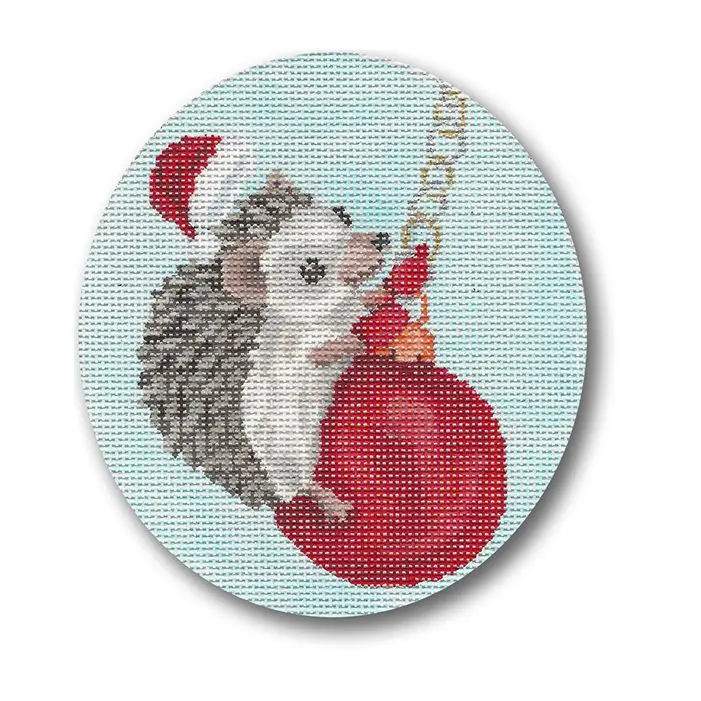 A cross stitch picture of a hedgehog holding a christmas ball.